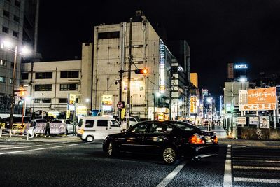 Cars on illuminated road against sky at night