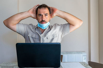 Frustrated man wearing flu mask sitting at office