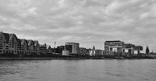 River with buildings in background against cloudy sky