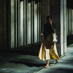 Full length of woman standing against wall