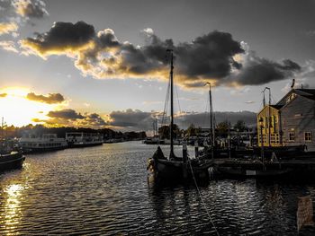 Sailboats moored at harbor against sky during sunset