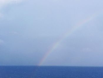 Scenic view of rainbow over sea against sky