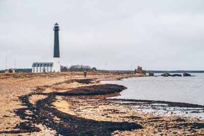 Lighthouse by sea against sky