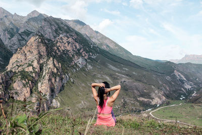 Rear view of woman sitting against mountains