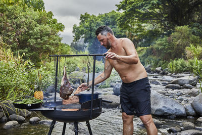 Chef preparing barbecue at campsite kitchen near stream