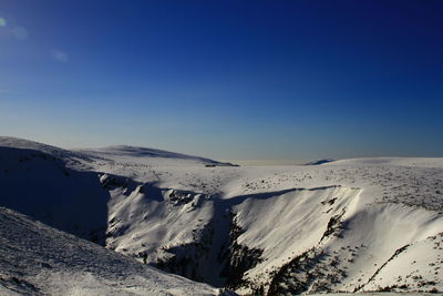 Scenic view of snowcapped mountains against clear blue sky