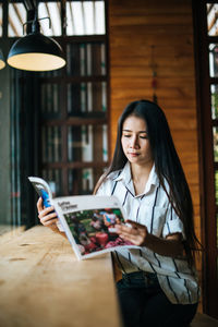 Young woman using phone while sitting on table