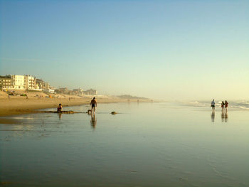 People on beach against clear sky