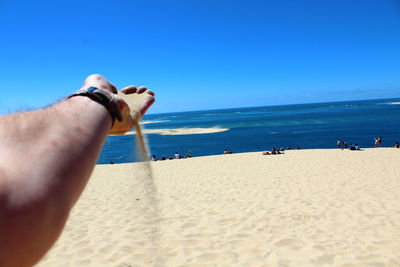 People on beach against clear blue sky