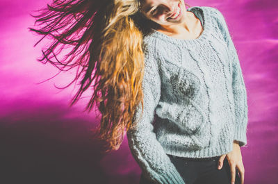 Midsection of woman standing against pink wall