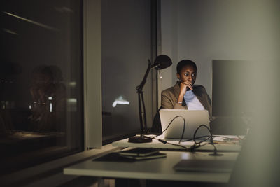 Businesswoman using computer while working last minute in office at night