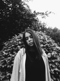 Close-up of young woman standing against trees