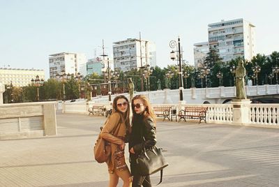 Full length of young woman against railing in city