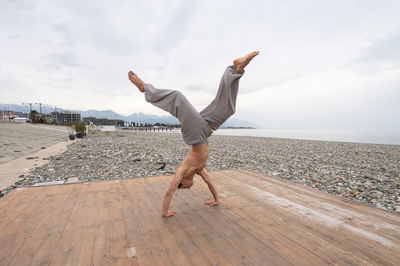 Full length of man doing handstand against sky