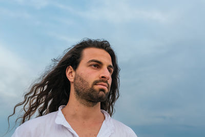 Portrait of young man looking away against sky