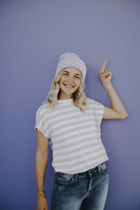 Portrait of young woman standing against blue background