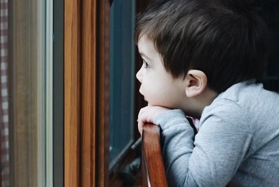 Close-up of boy looking through window