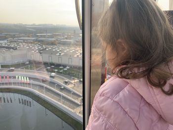 Rear view of woman looking through window