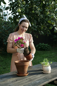 A woman replants an impatiens in a new pot