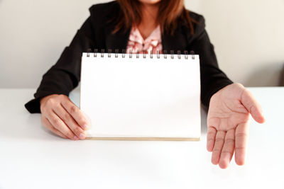 Midsection of woman holding paper against white background