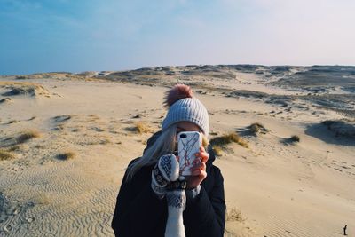 Young woman photographing with phone at beach