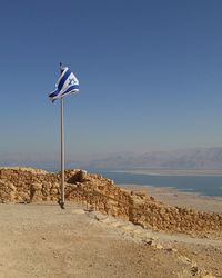 Israeli flag by lake against clear blue sky