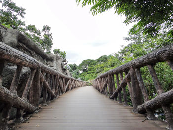 View of footbridge in forest against sky