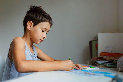 Side view of boy drawing at home