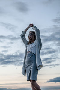 Woman with arms raised standing against sky