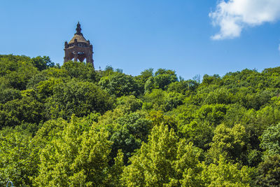 Low angle view of trees and building against sky
