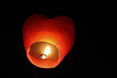 Low angle view of illuminated lantern against black background