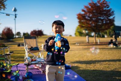 Boy playing on field against sky