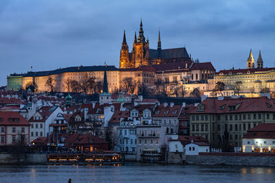 View of buildings by river in city against sky