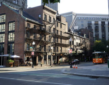 Road by buildings in city against sky