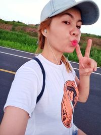 Portrait of young woman wearing hat standing against sky