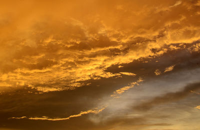 Low angle view of sunlight streaming through clouds during sunset