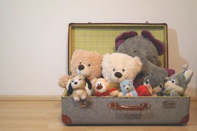 Various stuffed toys in suitcase on hardwood floor at home interior