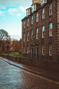 Buildings by street against sky in city