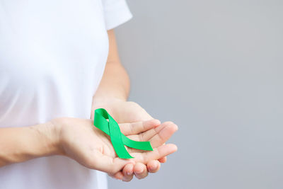 Close-up of man holding hands over white background