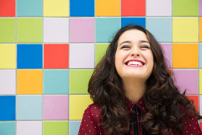 Portrait of a smiling young woman against wall