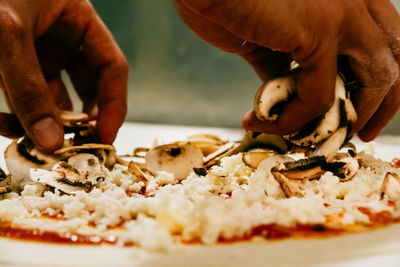 Cropped hands of man garnishing pizza