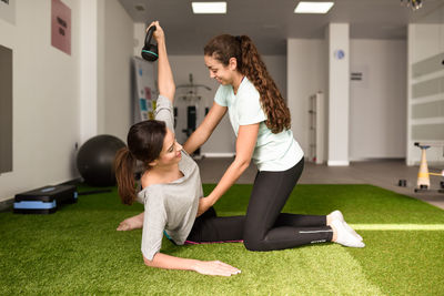 Instructor assisting woman exercising at gym