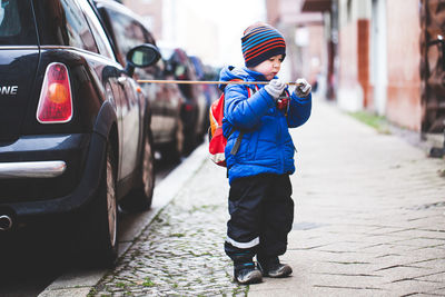 Full length of boy on car moving in city