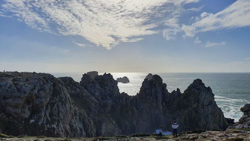 Rock formations on sea shore against sky