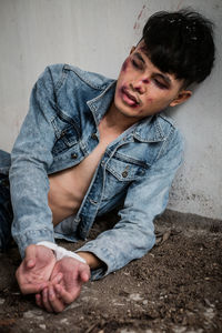 Close-up of wounded man sitting against column