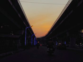 Cars on road in city against sky during sunset