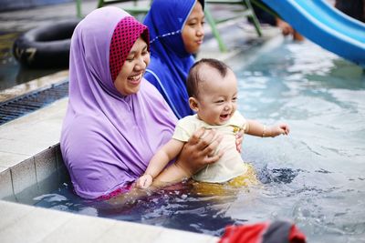 Smiling woman with daughter and sister sitting in pool