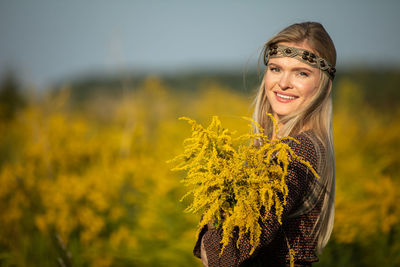 Portrait of smiling young woman standing against blurred background