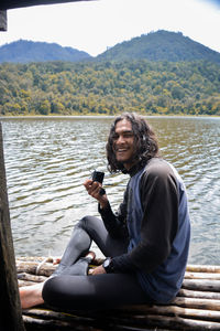 Portrait of young woman using mobile phone in lake