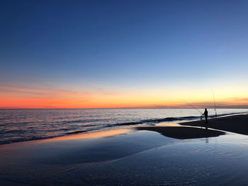 Silhouette person on beach against sky during sunset